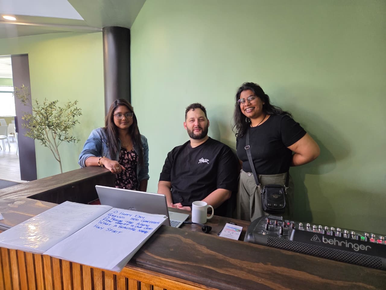 Three members of the team at the welcome counter, beside the sound desk