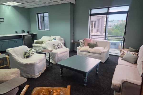 The Lounge Room: sofas and armchairs around a coffee table, a kitchenette, and a balcony door